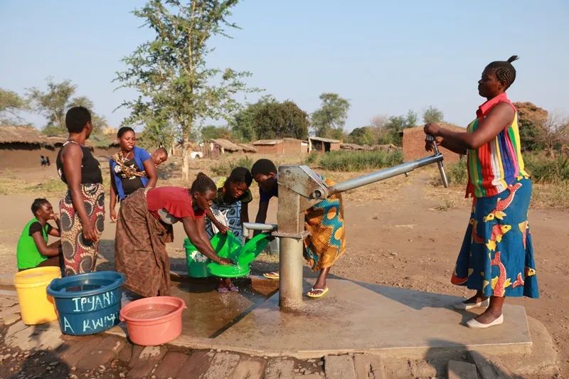 Villagers gathered around a communal hand pump, filling containers with safe water